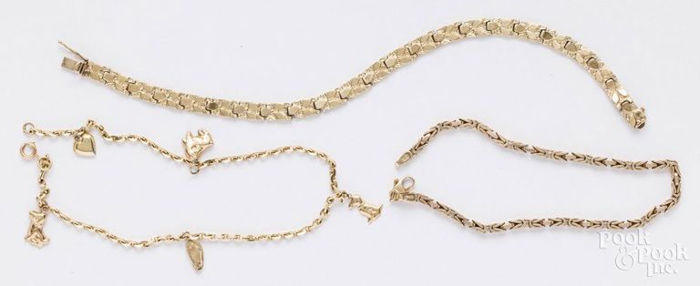 Three gold bracelets, one with charms