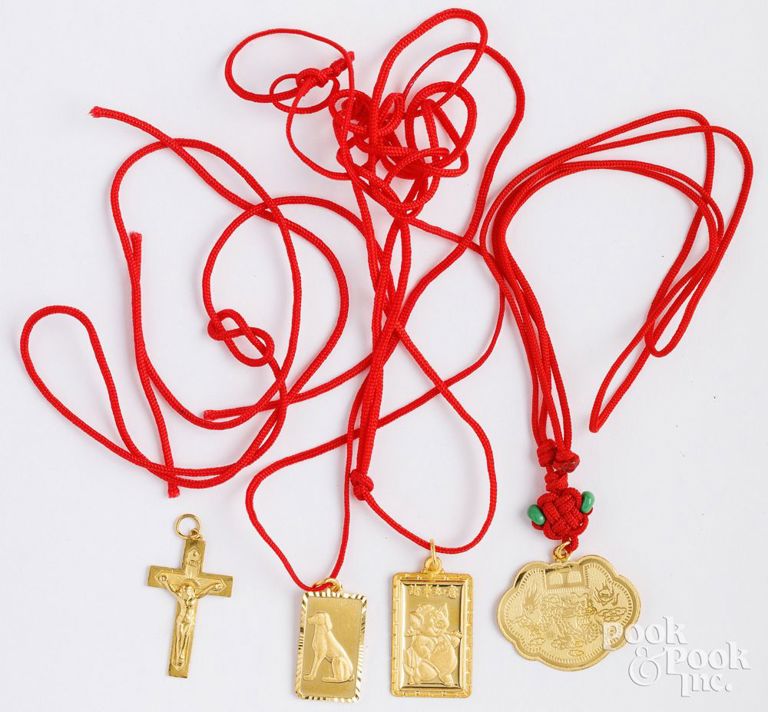 Four 22k yellow gold pendants on red cord necklaces